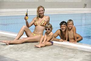 une jeune famille heureuse s'amuse à la piscine photo