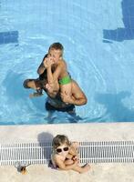 une jeune famille heureuse s'amuse à la piscine photo