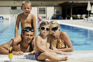 une jeune famille heureuse s'amuse à la piscine photo