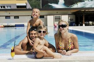 une jeune famille heureuse s'amuse à la piscine photo