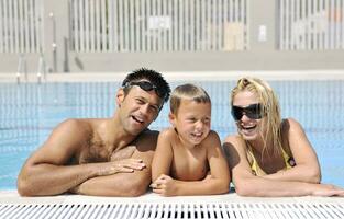 une jeune famille heureuse s'amuse à la piscine photo