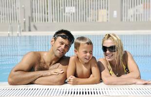 une jeune famille heureuse s'amuse à la piscine photo