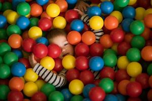 garçon ayant amusement dans des centaines de coloré Plastique des balles photo