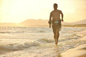 portrait d'un jeune homme kitsurf à la plage au coucher du soleil photo