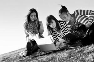 groupe d'adolescents travaillant sur un ordinateur portable en plein air photo