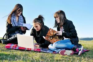 groupe d'adolescents travaillant sur un ordinateur portable en plein air photo