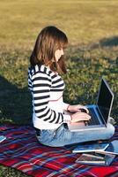 jeune adolescente travaille sur un ordinateur portable en plein air photo