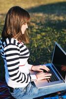 jeune adolescente travaille sur un ordinateur portable en plein air photo