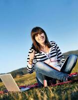 jeune adolescente travaille sur un ordinateur portable en plein air photo