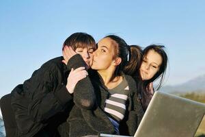 groupe d'adolescents travaillant sur un ordinateur portable en plein air photo