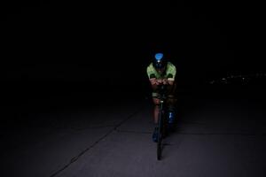 athlète de triathlon faisant du vélo rapidement la nuit photo