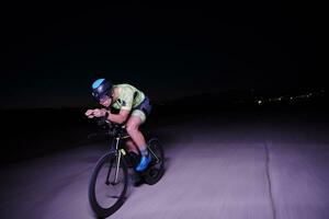 athlète de triathlon faisant du vélo rapidement la nuit photo