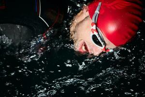 athlète de triathlon nageant dans la nuit noire portant une combinaison de plongée photo