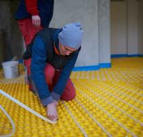 Ouvriers installant un système de chauffage par le sol photo