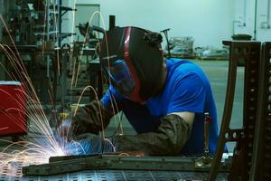 soudeur professionnel de l'industrie lourde travaillant à l'intérieur de l'usine, porte un casque et commence à souder. mise au point sélective photo