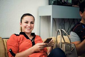 la femme est assise sur le canapé de son lieu de travail et utilise son smartphone pendant la pause. mise au point sélective photo