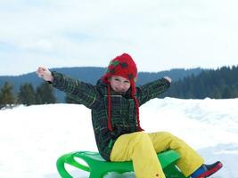 heureux jeune garçon s'amuser pendant les vacances d'hiver sur la neige fraîche photo