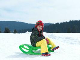 heureux jeune garçon s'amuser pendant les vacances d'hiver sur la neige fraîche photo