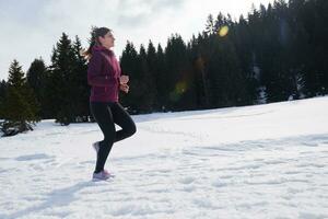 jeune femme faisant du jogging en plein air sur la neige en forêt photo