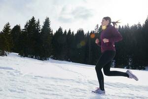 jeune femme faisant du jogging en plein air sur la neige en forêt photo