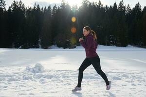 jeune femme faisant du jogging en plein air sur la neige en forêt photo