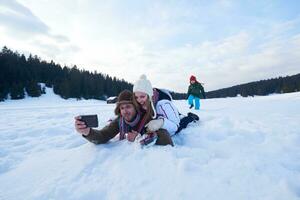 un couple romantique s'amuse dans la neige fraîche et prend un selfie photo