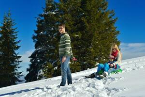 famille s'amusant sur la neige fraîche pendant les vacances d'hiver photo