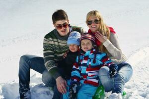 famille s'amusant sur la neige fraîche pendant les vacances d'hiver photo