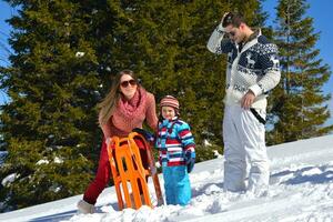 famille s'amusant sur la neige fraîche en hiver photo