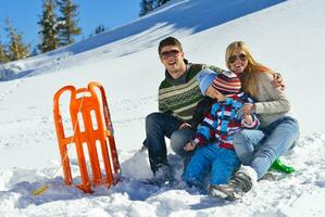 famille s'amusant sur la neige fraîche pendant les vacances d'hiver photo