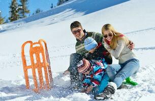 famille s'amusant sur la neige fraîche en hiver photo