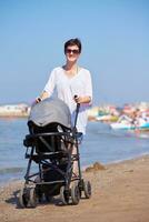 mère marchant sur la plage et poussant le landau photo