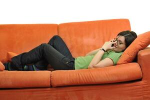 heureuse jeune femme se détendre sur un canapé orange photo