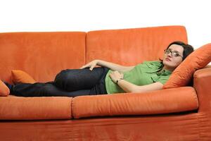 heureuse jeune femme se détendre sur un canapé orange photo