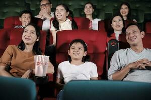 asiatique famille public jouit en train de regarder cinéma ensemble à film théâtres. enfant et Parents avoir intérieur divertissement mode de vie avec performance art montre, content et de bonne humeur avec pop corn et une sourire. photo