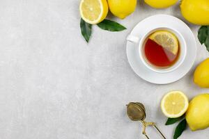 tasse de thé avec Frais citrons et feuilles sur lumière gris béton Contexte. chaud en bonne santé boisson. immunitaire la défense, vitamine c. Haut voir. copie espace. photo