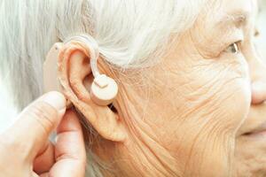 médecin installer audition aide sur Sénior patient oreille à réduire audition perte problème. photo