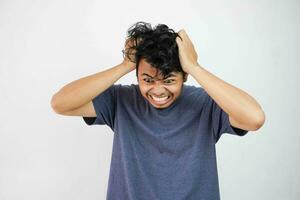 en colère et furieux asiatique homme sur une blanc Contexte. il tire en dehors le sien cheveux dans une rage photo