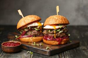 deux hamburgers avec cornichons et des œufs sur une en bois planche photo