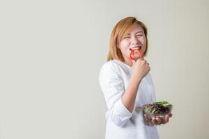 belle femme debout tenant un bol de salade mangeant des légumes photo