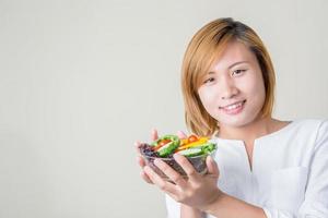 mains de belle femme tenant un grand bol de salade de légumes frais. photo
