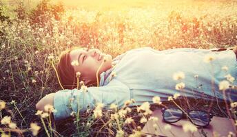 jeune hipster allongé sur le champ de pissenlit smiley dans le ciel. photo