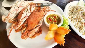 crabes bouillis avec sauce aux fruits de mer sur une assiette blanche. photo