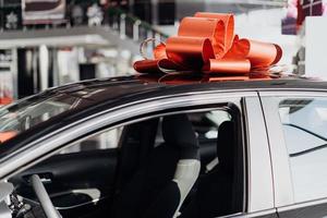 la nouvelle voiture est enveloppée dans un arc rouge. beau concept de cadeau photo