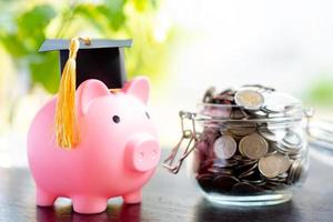 économisez des pièces d'argent dans un pot d'herbe avec tirelire et chapeau de graduation, photo