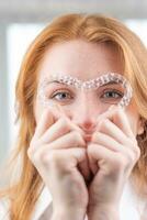 dentaire soins.souriant fille avec rouge cheveux en portant cœur en forme de aligneurs photo