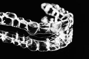 invisible dentaire les dents supports dent aligneurs sur noir Contexte. Plastique un appareil dentaire dentisterie retenues à redresser dents. photo