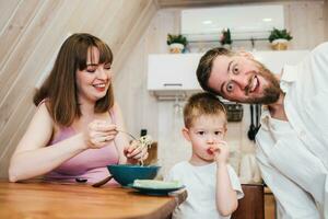 content famille en mangeant Pâtes dans le cuisine photo