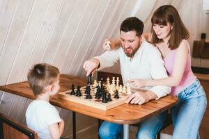 Enceinte maman en train de regarder papa et fils jouer échecs à le table photo