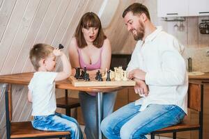 content famille mère, papa et leur fils en jouant échecs dans le pièce photo